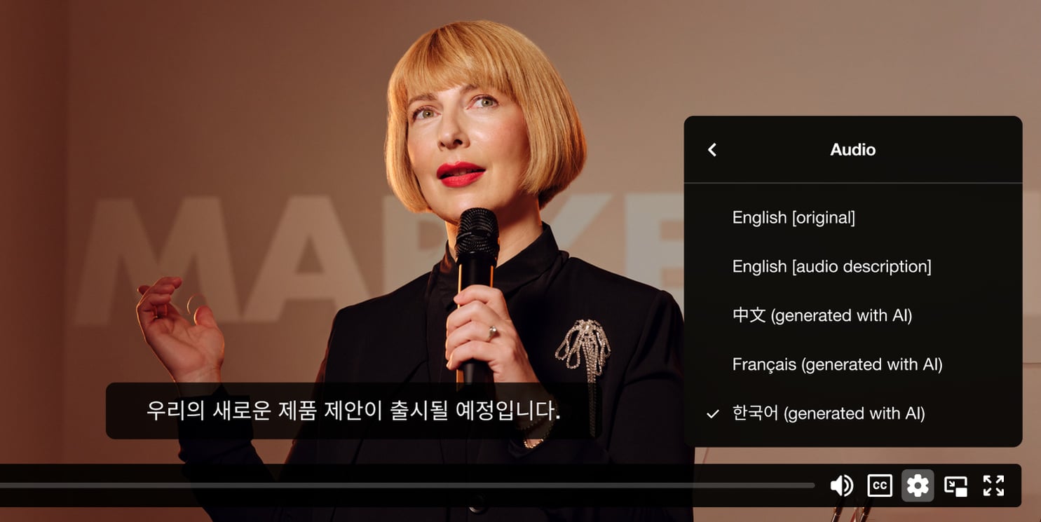 Video recording of a woman speaking to an audience with a selector open to switch the language she is speaking in