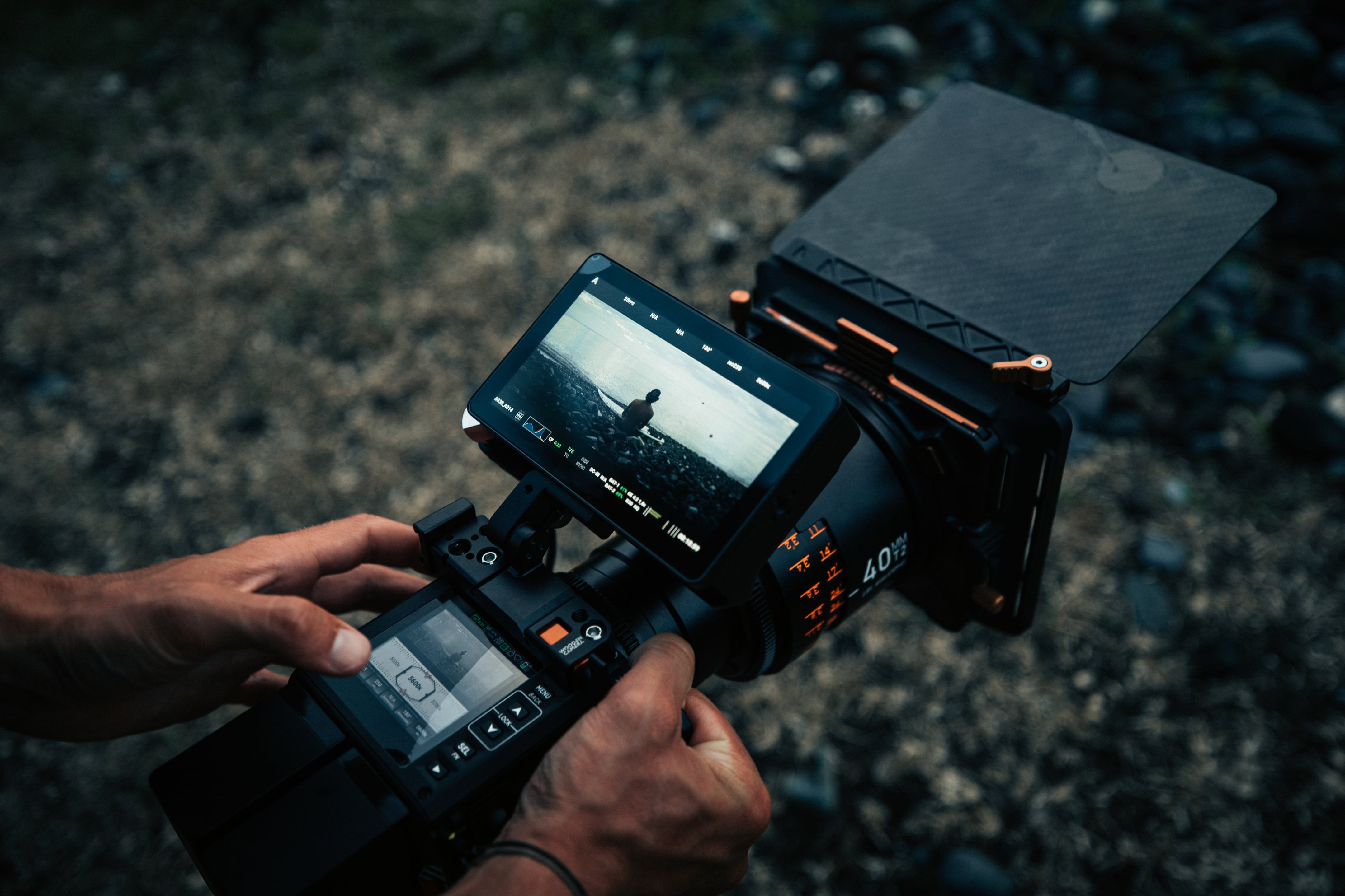 Filmmaker holding a camera with an overhead visor outside