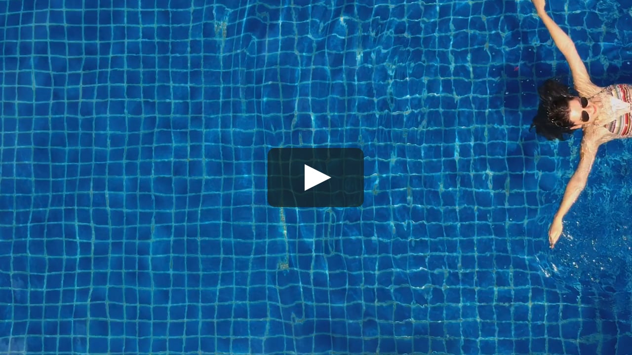 Slow Motion Aerial Shot Of A Bikini Clad Woman Swimming On Her Back In