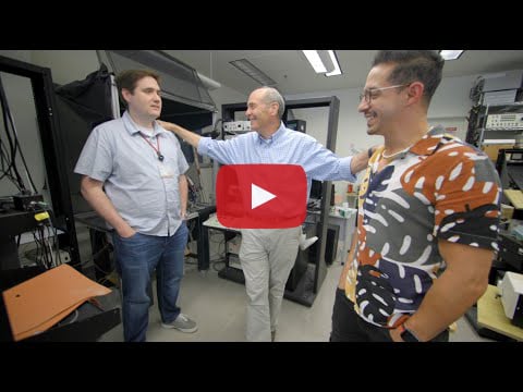 David Stoppel, Mark Bear and Hector Jesus-Cortes stand in a lab. Bear stands in the center and has a hand on each postdoc's shoulder.