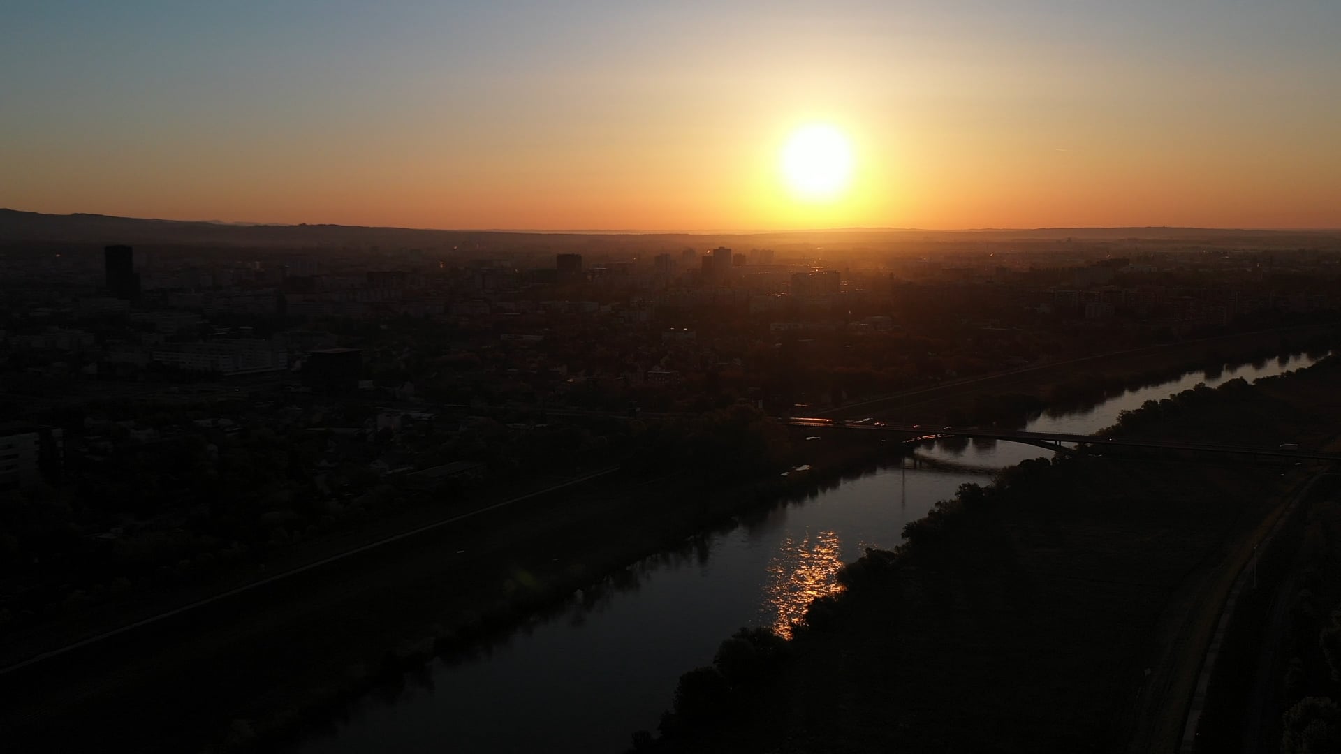 Sunrise above river in the city