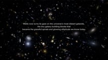 Image of a field of galaxies. Text in the center reads "Webb now turns its gaze on the universe's most distant galaxies, the tiny galaxy building blocks that became the graceful spirals and glowing ellipticals we know today."