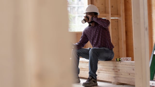 Break time! Contractor takes a break while he sips on his coffee and scrolls through his social media. 