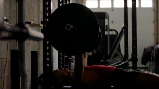 A young fit male powers through a final set on the bench press. 
