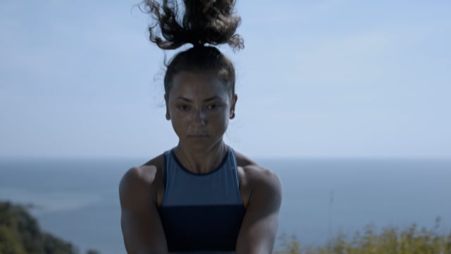Powerful woman exercises on a hilltop in order to achieve her goals. Focused and determined.