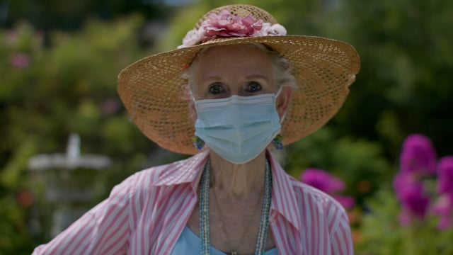 Senior citizen gardening while wearing a protective face mask due to global pandemic. Gardening and enjoying retirement with social distancing and safety.