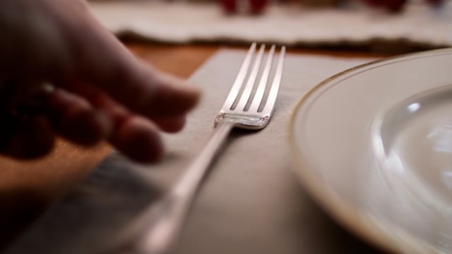 Placing beautiful silverware as the table is set for a festive meal. 