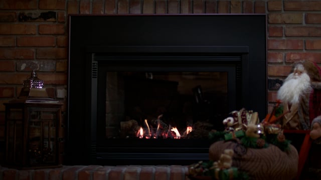 A warm and inviting fire roaring in a fireplace, decorated and dressed for the christmas holidays. 