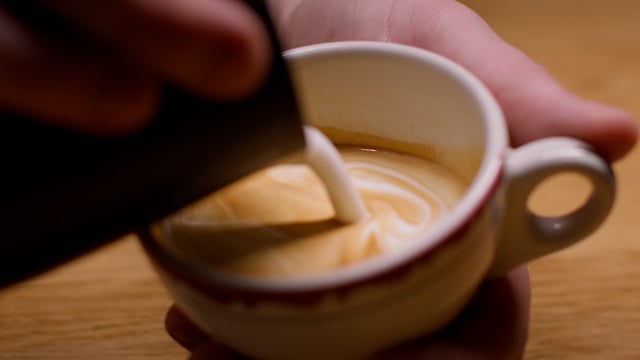 The final touches on a rich, decadent cappuccino as the steamed milk is applied. Latte art. 