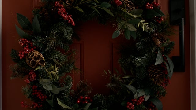 A beautiful christmas wreath is hung in the front door of a home for the holidays. 