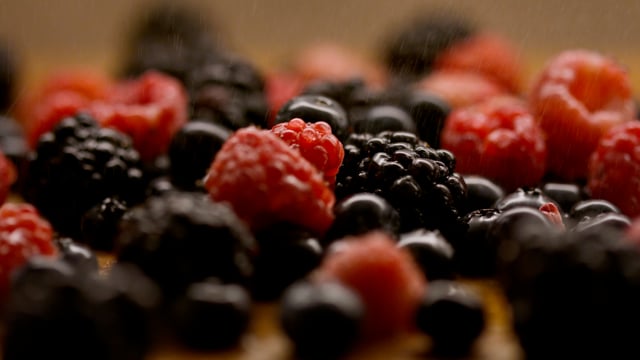 An assortment of fresh, organic berries being misted to stay fresh. 