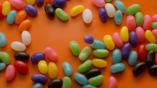 Sweet and colourful jelly beans fall down into frame in slow motion. 