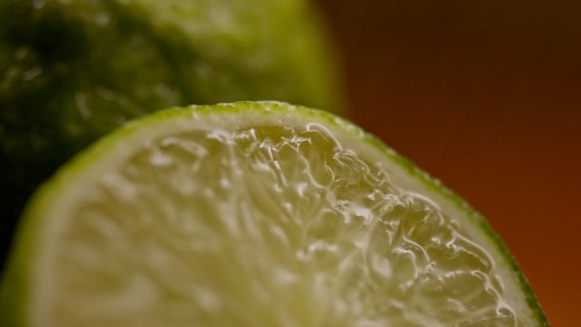 Macro shot of fresh cut organic limes being misted on the cutting board. 