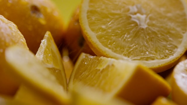 Macro shot of juicy organic lemon slices, tumbling in slow motion. 