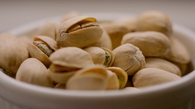 Healthy organic pistachios pour into a ceramic bowl in slow motion.  