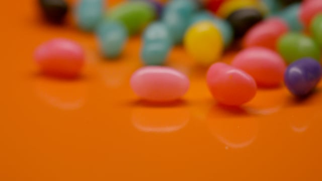 Sweet colourful jelly beans pouring into frame in slow motion. 