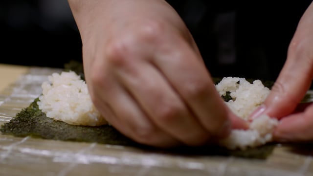 Japanese cuisine preparation. Creating amazing sushi and sashimi at a high-end sushi restaurant. Working with rice in a roll. 