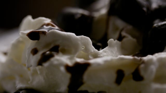 Sweet and fluffy whipped cream with decadent chocolate sauce being drizzled atop it. 