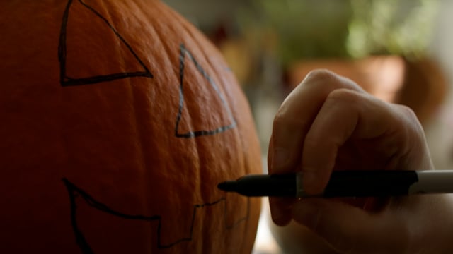 Finishing touches on drawing a jack-o-lantern face on a pumpkin. 