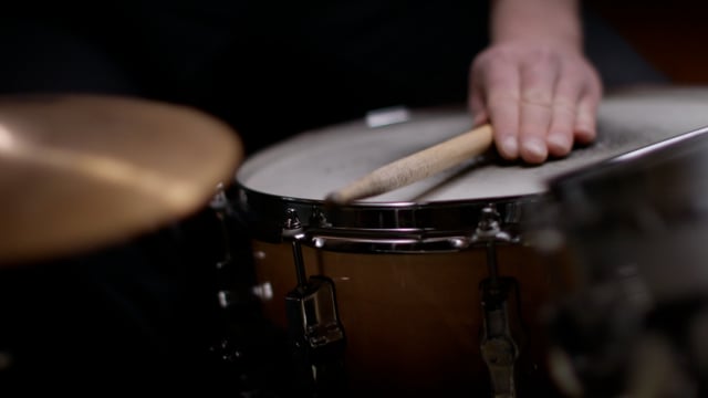 Rim shot on snare from drummer during performance.  