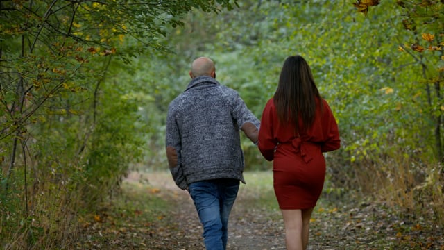 A young couple walking through the natural beauty of the changing colours of fall. 
