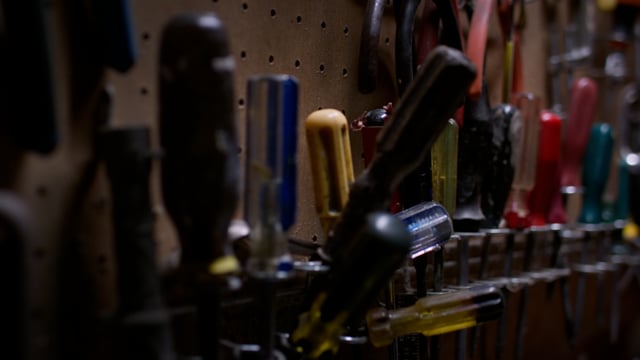 A well-stocked workbench is full of tools hanging on a pegboard. 

