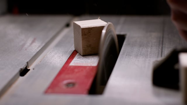 Cross-cutting a piece of wood on a table saw for a construction project. 