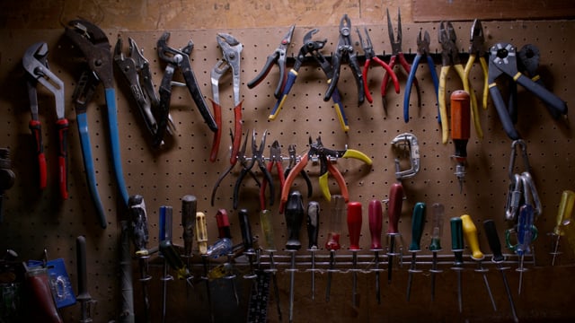 An assortment of hand tools hung over a well used workbench. 