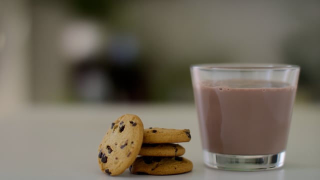 Chocolate Milk and cookies. Milk pouring into glass.