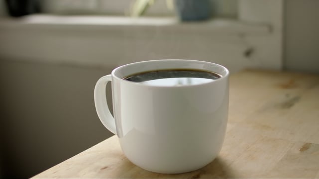 Fresh brewed cup of coffee. White coffee mug with black coffee on a wooden table.