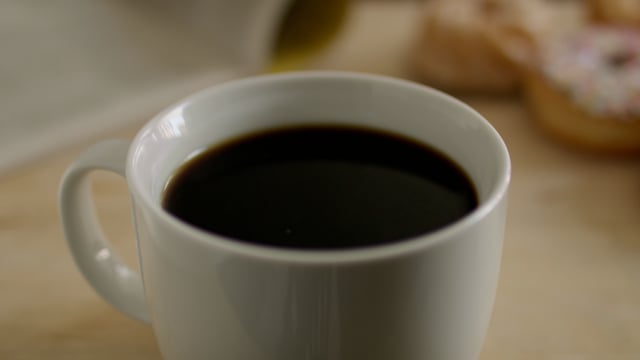 Dunking doughnut into a cup of coffee. Slow-motion doughnut dunk into a cup of coffee.