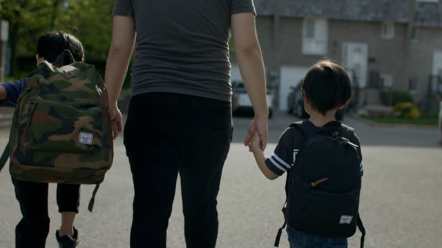 Father walks with two sons to school holding hands. 