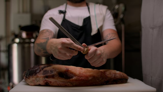 Chef sharpening his knife as they prepare to cut into this mean cut of meat.  