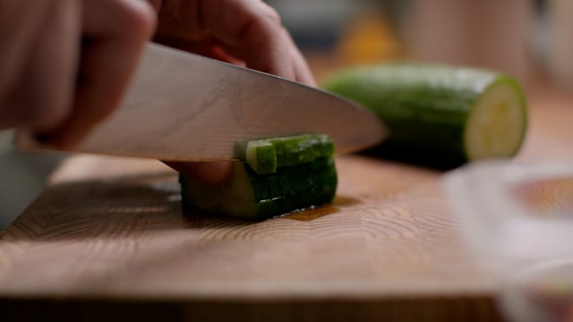 Chef prepares mise en place by cutting cucumbers 