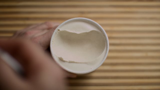 Ice cream in a cup eaten with a scoop. Top-down ice-cream hand video. 