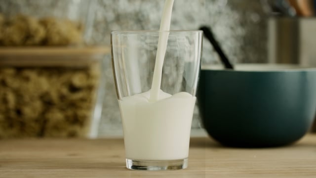A glass of milk in slow motion. Pouring milk in transparent glass. 