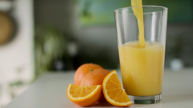 Healthy orange juice in a glass and oranges. Juice splash slow-motion footage. 