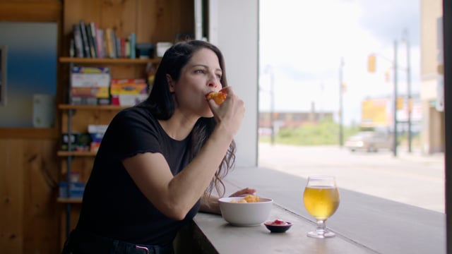 Super cheesy. A woman takes a bite of a super stringy fried cheese curd at a newly opened restaurant.