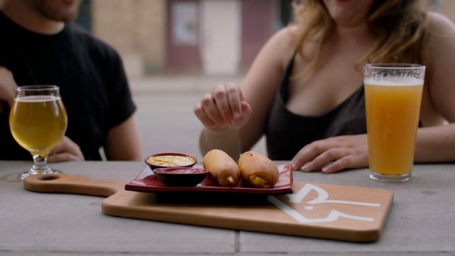 A young couple enjoys beers and corn dogs at a local independent restaurant. 