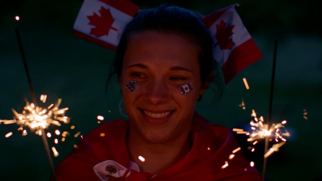 A woman celebrates Canada day with sparklers and miniature flags in her hair.