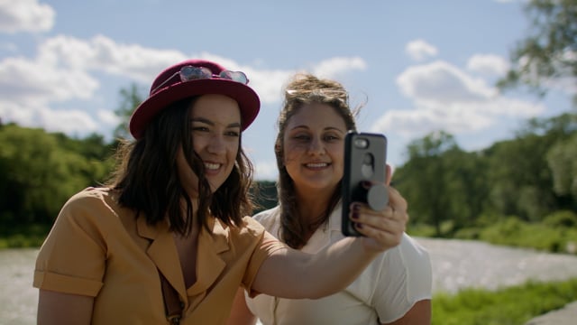 Friends take a selfie in a beautiful park in front of a river. 