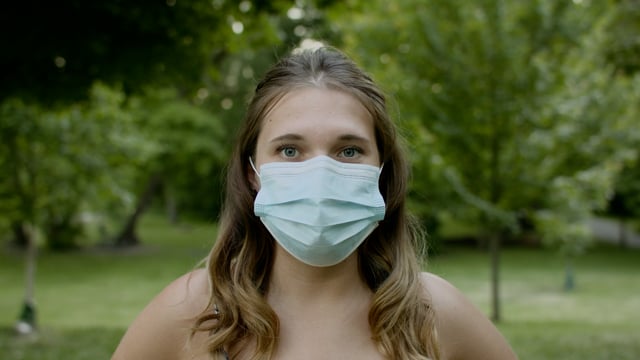 Portrait of a young woman wearing a mask in a beautiful natural setting. 