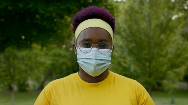 A portrait of a confident black woman. An essential worker wearing a mask. 