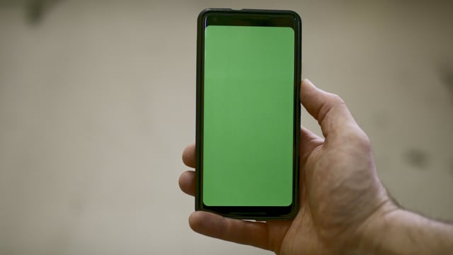 Green screen smartphone held by a male. Technology footage. Great for close-up scenes.