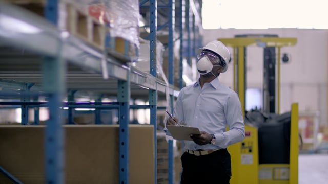 Examining inventory in a mask. A manager checks warehouse safety and inventory.