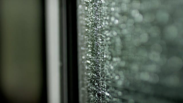 Raindrops fall on a window during a thunderstorm.
