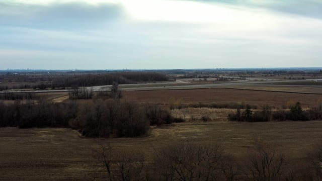Rolling rural vista with trees in the foreground in early spring. 
