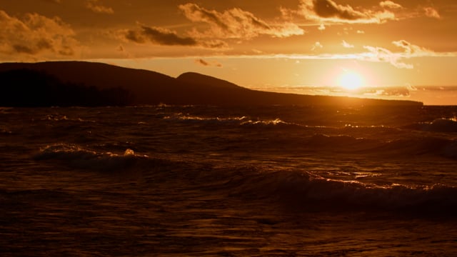 Beautiful sunset over a magnificent mountain. Waves rolling over the shores. 
