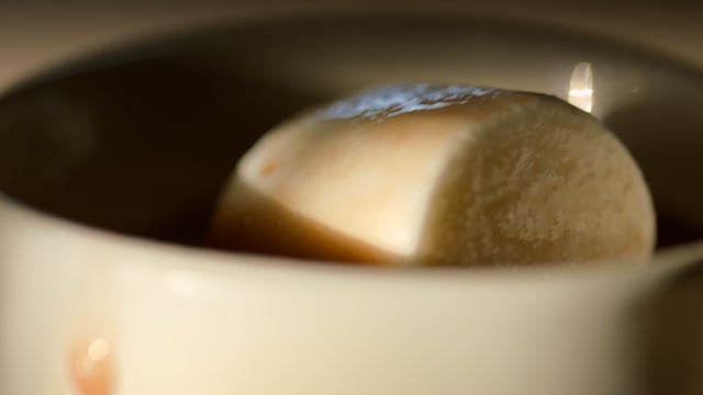 Extreme close up of morning coffee resting on the counter as steam rises off of its surface.