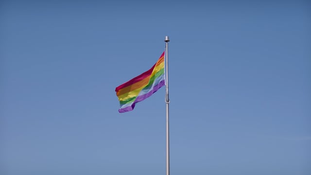 A pride flag waving in the summer sun. 